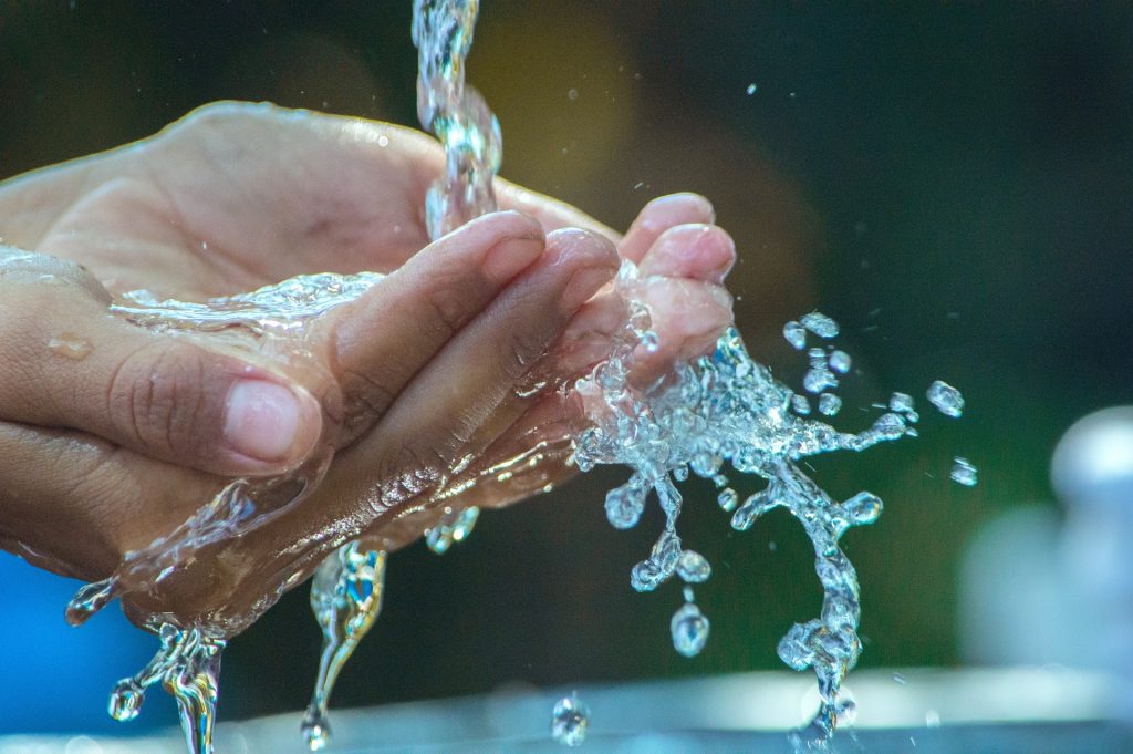 Auf dem Bild sieht man zwei Hände, die sich unter fließendem Wasser waschen.